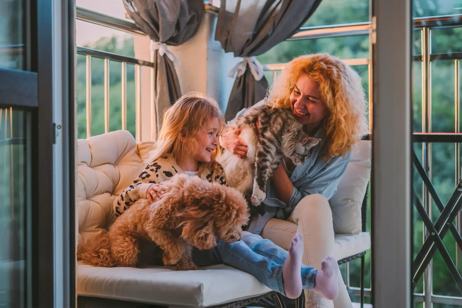 A woman with her daughter on a couch with a dog and a cat.